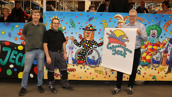 Drei Männer stehen lächelnd vor Umzugswagen, rechts mit Schild in der Hand