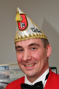 Ein Mann mit Narrenkappe, rotem Sakko und Fliege
