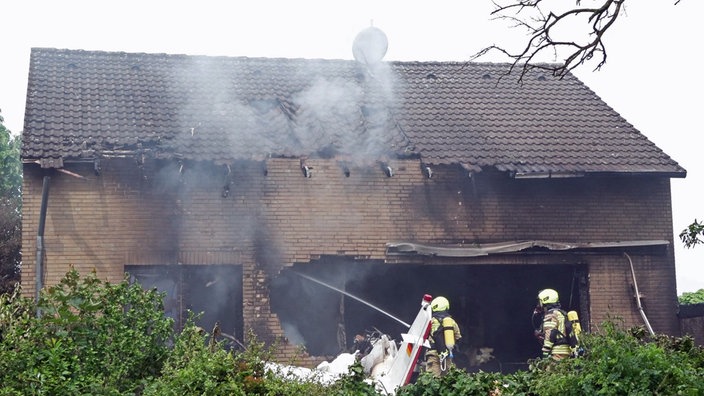 Feuerwehrkräfte löschen einen Brand nachdem ein Kleinflugzeug auf ein Haus in Korschenbroich gestürzt ist.