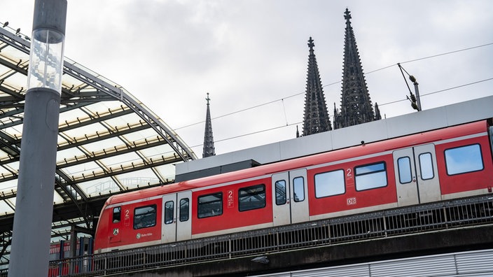 Eine S-Bahn fährt in Köln Hauptbahnhof mit Dom im Hintergrund ein 