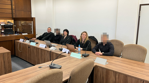 Gerichtssaal mit fünf Personen, unter anderen Angeklagter und Verteidiger