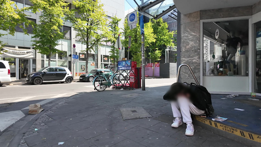 Auf einer Treppe sitzt ein Mann mit weißer Hose und schwarzer Jacke.