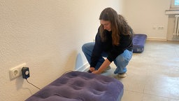 Junge Frau in der Hocke beim  Aufpumpen einer Luftmatratze