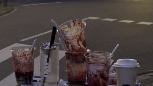 Mehrere Plastikbecher stapeln sich auf einer Mülltonne