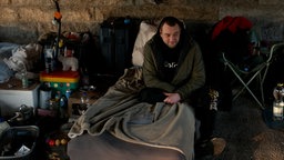 Pawel sitzt auf seinem Nachtlager unter der Zoobrücke.