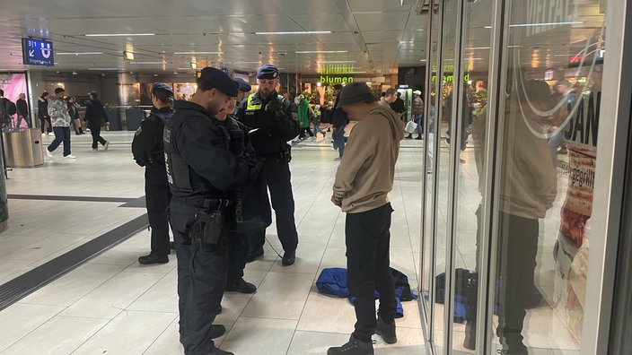Polizeibeamte kontrollieren im Hauptbahnhof Düsseldorf einen Mann