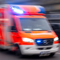 Auf dem Foto ist ein Krankenwagen der Feuerwehr mit Blaulicht, der über eine Straße fährt.