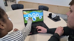 Ein Mädchen zeigt auf den Bildschirm eines Laptops
