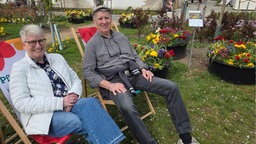 Anne und Uwe Bünzel, zwei der ersten Besucher der Landesgartenschau 2026 in Neuss, sitzen auf Liegestühlen und genießen einen Moment Ruhe.