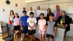 Kinder und Mitglieder des Rotary Club Leverkusen, die einen Spendenscheck hochhalten.