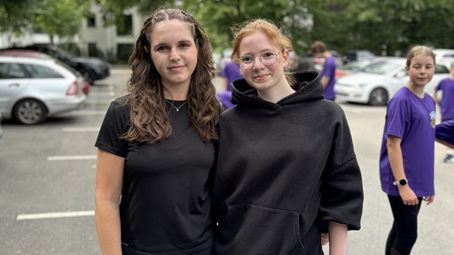 Schülerin Julia Breidel (l.) und eine Klassenkameradin in schwarzer Kleidung Arm in Arm.