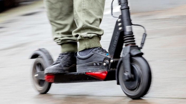 E-Scooter mit schwarzen Schuhen