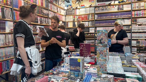 Zwei Männer unterhalten sich an einem Buchstand mit Mangas