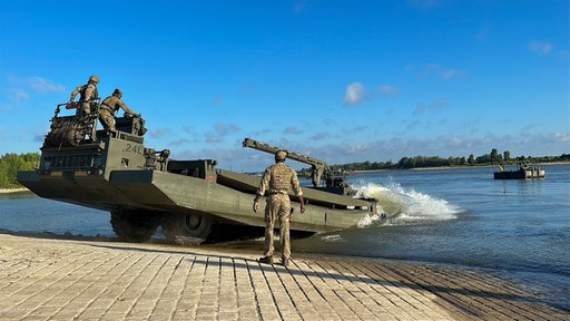 Ein Militärfahrzeug fährt an einer Anlegestelle in den Rhein