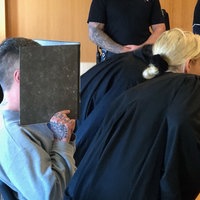 Angeklagter im Gerichtssaal, hält sich einen Ordner vor das Gesicht, im Vordergrund eine Anwältin