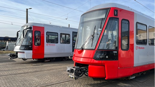 zwei rot- und graulackierte Straßenbahnen 