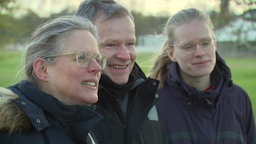 Zwei Frauen und ein Mann blicken in die Ferne 