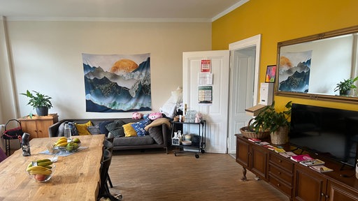Ein Aufenthaltsraum mit großem Esstisch, Sofa und Fernseher der Notschlafstelle Düsseldorf.