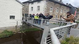 NRW-Umweltminister Oliver Krischer auf einer Brücke über die Inde im Gespräch mit Journalisten bei der Vorstellung des Modellprojekts