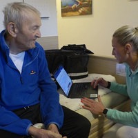 Eine DIHVA mit Laptop neben einem Senioren.