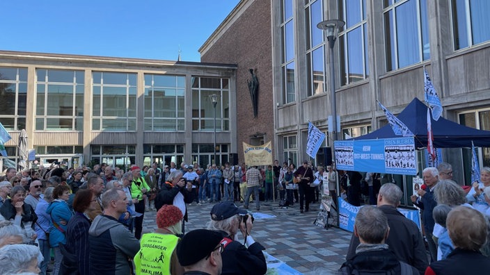 Vor dem Kölner Rathaus stehen viele Menschen, einige haben Plakate, ein Stand des Bündnis Verkehrswende in Blau steht in der Mitte