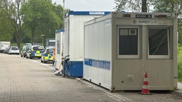 Auf dem Bild ist ein Container und mehrer Polizeiautos zu sehen.