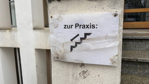 abgeblättertes Schild mit der Aufschrift: "Zur Praxis"