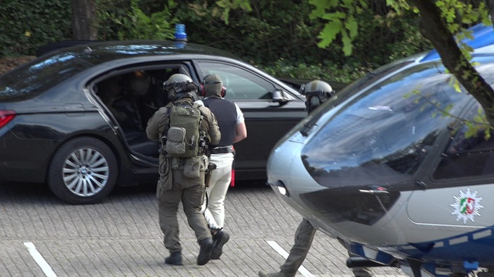 Der Angeklagte wird vom Helikopter zu einem Fahrzeug der Polizei gebracht.