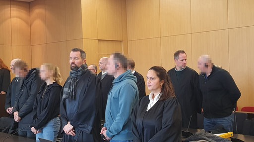 Die Angeklagten sitzen neben ihren Anwälten im Gerichtsaal. 