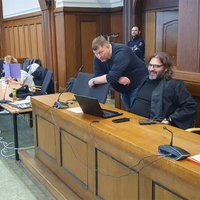 Teil der Angeklagten und ihre Verteidiger sitzen im Gerichtsaal