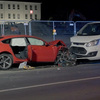 Roter Sportwagen mit verbeulter Motorhaube. Zerquetschtes Fahrrad davor und direkt am Fahrrad ein kleiner weißer Transporter