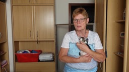 Katzenpflegerin Gabi Wettläufer steht mit einem Katzenbaby in ihrer Wohnung