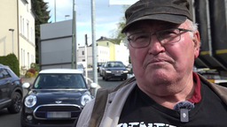 Zu sehen ist Werner Schüttler, der in die kamera spricht. Er ist Bewohner der Stadt Lüdenscheid der zu der Verkehrssituation, die im Hintergrund zu sehen ist, befragt wird 
