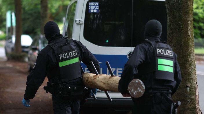 Polizisten tragen einen Rammbock bei einem Einsatz in Leverkusen.