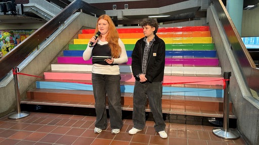 zwei Schüler:innen der Gesamtschule vor Regenbogentreppe