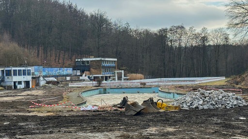 Abrissarbeiten am Freibad Eschbachtal, leeres Schwimmbecken und Bauschutt im Vordergrund