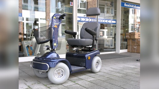 Ein elektrischer Krankenfahrstuhl vor einem Schaufenster