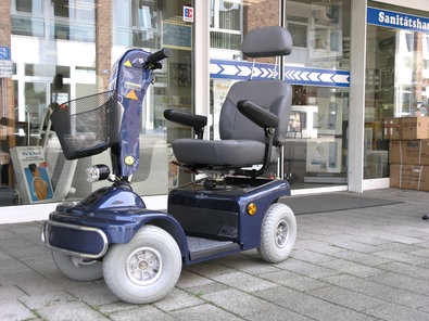 Ein elektrischer Krankenfahrstuhl vor einem Schaufenster