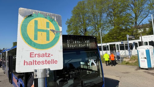 Ein Bus steht hinter einem vergilbten Schild mit dem Aufdruck "Ersatzhaltestelle"
