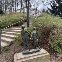 Eine Bronze-Skulptur steht auf einem Sockel vor einer Treppe am Michaelsberg