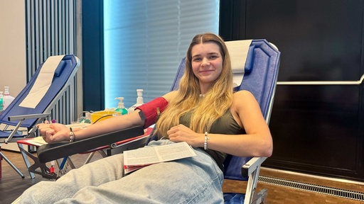 Eine junge Frau liegt auf einer blauen Liege und spendet Blut