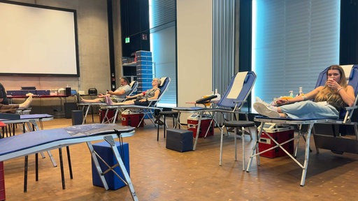 Drei Menschen liegen auf blauen Liegen und spenden Blut