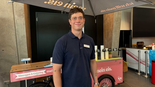 Ein Mann steht vor einem pinken Eiswagen