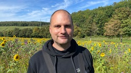 Mann steht auf der Blumenwiese 