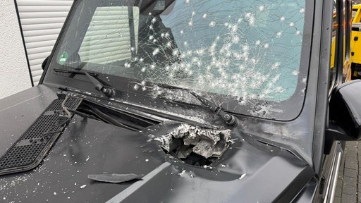 Ein riesiges Loch klafft in der Motorhaube eines Autos, die Scheiben sind gesplittert