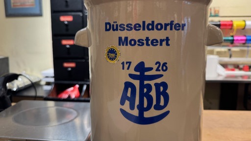 Keramikkübel mit der Aufschrift "Düsseldorfer Mostert. ABB. Seit 1726". 