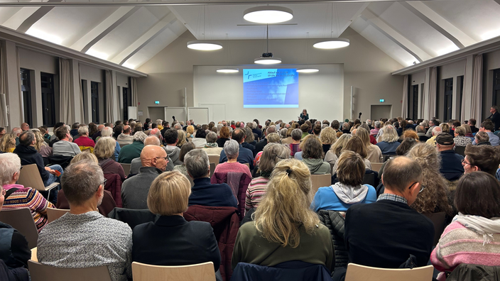 Viele Menschen von hinten schauen auf eine Präsentation