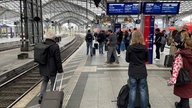 Bahnkunden warten am Gleis auf den nächsten Zug