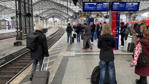 Bahnkunden warten am Gleis auf den nächsten Zug