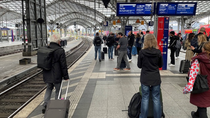 Bahnkunden warten am Gleis auf den nächsten Zug
